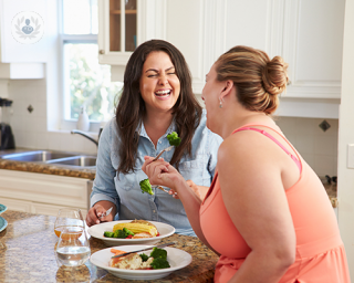 two women laughing while eating healthy food