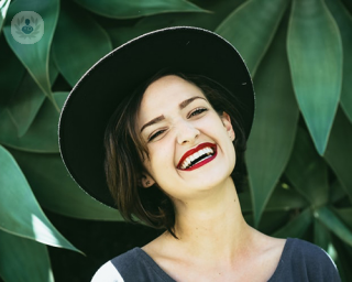 smiling woman wearing a hat and red lipstick
