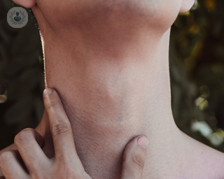 A person's hand touching the base of their neck
