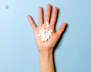 An outstretched hand with a batch of prescription drugs in its palm