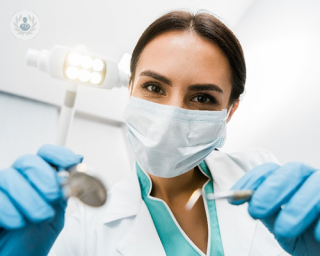 Dentist wearing blue gloves looking into the camera