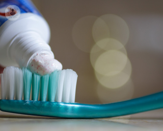 Toothpaste being applied onto a toothbrush. 