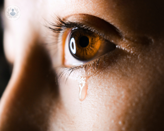 Close up photo of an eye with tears running down the cheek