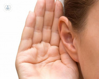 Closeup image of a girl holding up her hand to her ear
