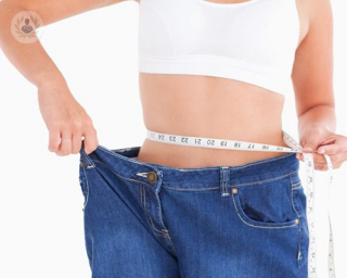 woman in oversized jeans measuring waist