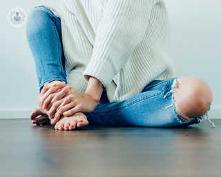 woman sat in ripped jeans with knee on show 