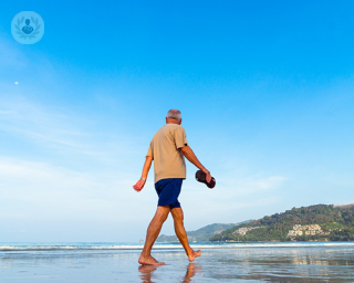 An elderly man taking a walk by the beach. 
