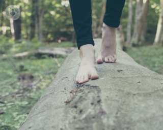 woman with bare feet walking on a log