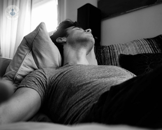 Man lying down trying to be comfortable, black and white