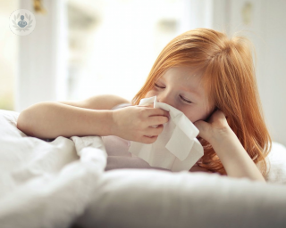 Young girl holding a tissue to her nose 