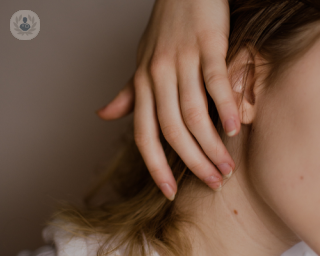 Woman with birthmark on neck lightly touching the area