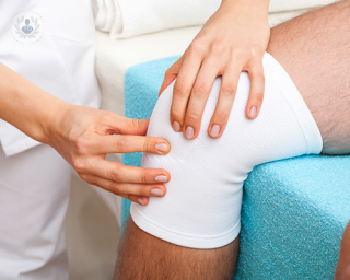 A patient getting their knee wrapped after undergoing arthroscopic surgery.