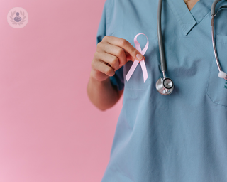 A doctor holding a breast cancer ribbon.