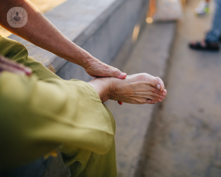 An elderly woman massaging her right foot