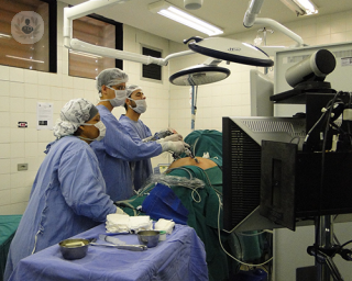 A surgeon in an operating theatre, performing a laparoscopic procedure.