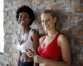 Two women in a gym wearing sports bra