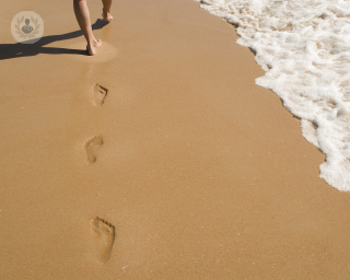 Woman walking on the beach leaving footprints behind her