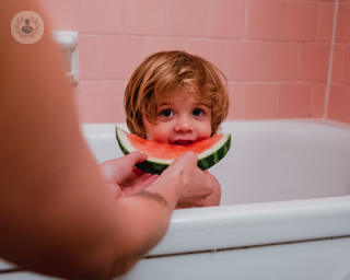 child in bath eating watermelon