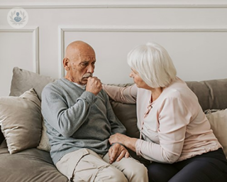 an image of a man coughing and his wife supporting him 