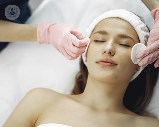 A young woman at an aesthetic medicine centre, preparing to undergo a chemical peel laser treatment. 