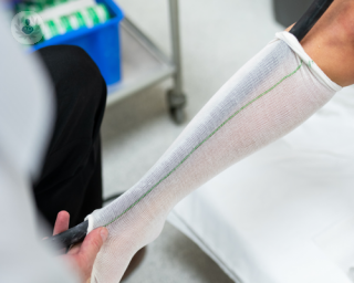 A white compression stocking with a green stripe being fitted in a clinic or surgery