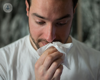 A man holding a tissue towards his nose