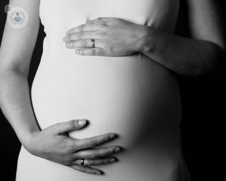 Black and white image of woman holding her pregnant belly