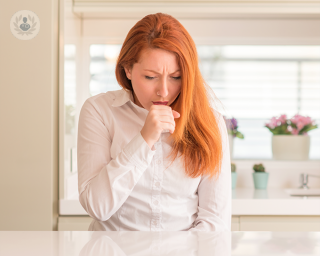 Woman sat down coughing into her hand