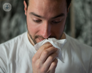 Man blowing his nose with a tissue