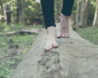 Woman's feet walking along a fallen tree