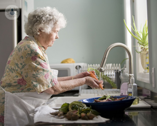 An older woman washes her hands at the kitchen sink at home. Older people are more at risk of having complications resulting from COVID-19.