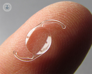 An intraocular lens resting on a finger tip