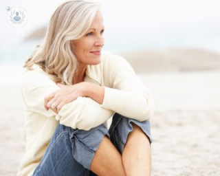 An older lady sitting on the beach