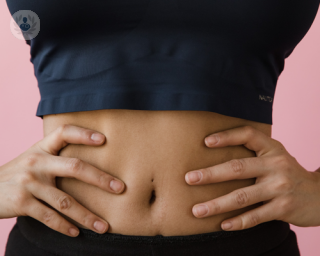 Close up of an athletic woman wearing gym clothes and hands on stomach