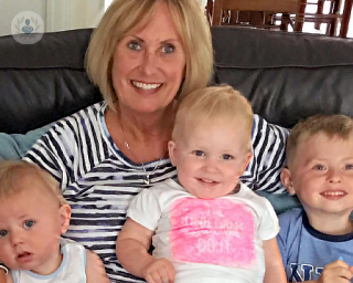 Ms Louise Kean and her grandchildren smiling, sat on a sofa