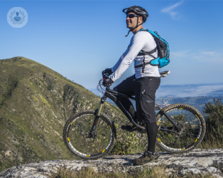 A picture of a man standing on a mountain top with a bike