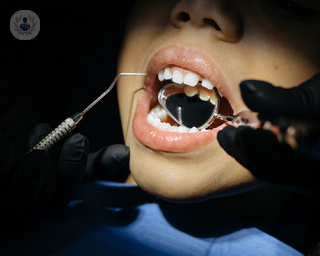 A dentist assessing a patient's teeth using dental instruments.