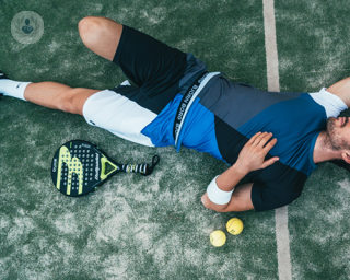 cute man lying on tennis court floor 