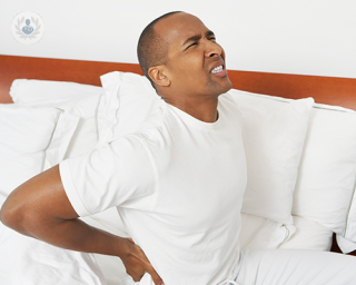 A man pressing his hands onto his lower back to relieve back pain