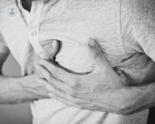 A young man pressing a hand to his chest, where his heart is, due to severe chest pain.