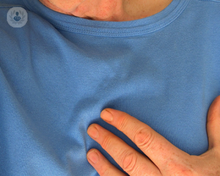 An elderly man holding a hand to his chest, where his heart is.