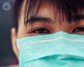 Close up of the face of a man wearing a surgical mask