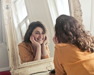 A happy woman looking in mirror.