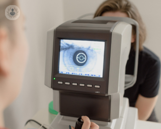 Woman ophthalmologist undertaking eye examination with patient's eye on the screen