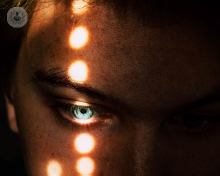 Man with lights shining on his face and right eye