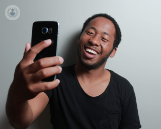Man smiling and holding up a smartphone and taking a photo of himself
