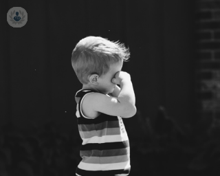 Black and white shot of little boy with allergies rubbing his eyes
