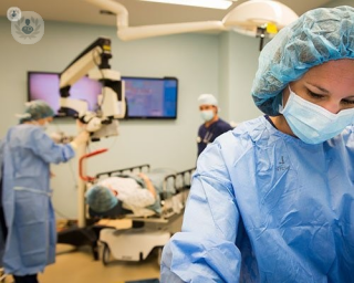 A patient in the operating room with several surgeons about to undergo hip replacement surgery.