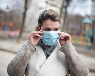 A woman adjusting her protective face mask while outside in public