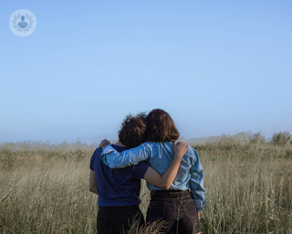 Two young people in a field hugging each other.